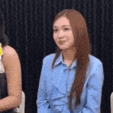 a woman in a blue shirt is sitting in a chair and smiling .