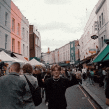 a group of people are walking down a busy street with a sign that says ' a ' on it