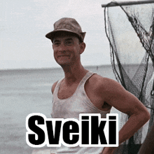 a man wearing a hat and a tank top with the word sveiki written on the bottom