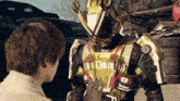 a man is touching a robot 's chest with his hand and the robot has the letter o on it