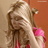 a woman in a pink shirt is covering her face with her hand and the name colucciyarango is above her