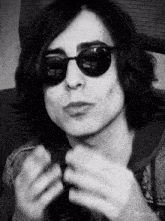 a black and white photo of a young man wearing sunglasses .