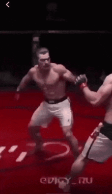 a man is kneeling down in a boxing ring while another man kicks him in the face
