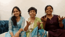 three women sitting on a couch with their hands up