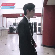 a man in a suit stands in front of a red door