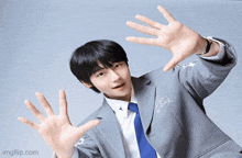a young man in a suit and tie reaches out his hands