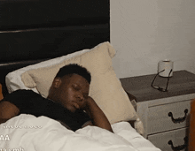 a man is sleeping in a bed with the letters aa on the bottom right