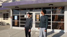 two men standing in front of a building with a sign on the door that says no dogs allowed