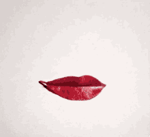 a red leaf is shaped like a woman 's lips on a white surface .