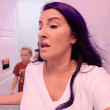 a woman with purple hair is wearing a white shirt and a gold necklace