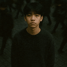 a young man in a black sweater is standing in front of a crowd of people