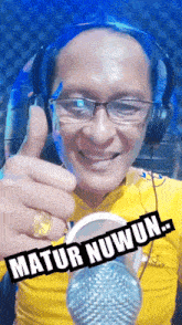 a man wearing headphones giving a thumbs up next to a microphone with the words matur nuwun written on it