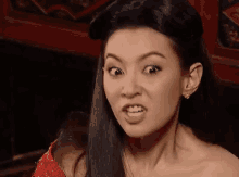 a woman in a red dress is making a funny face and looking at the camera .