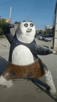 a statue of a panda bear is standing in the middle of a street .