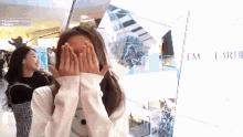 a woman covering her face with her hands in front of a sign that says em
