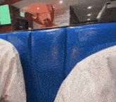 a person sitting in a booth with a blue cushioned seat