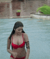 a woman in a red bikini is standing in a pool of water .