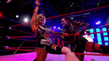 two women are wrestling in a ring and one of them is wearing a black and silver outfit