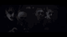 a group of people are standing in the dark with their faces painted .