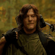 a man is carrying a bow and arrow on his shoulder .
