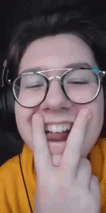 a person wearing glasses and headphones is making a peace sign with their hands .