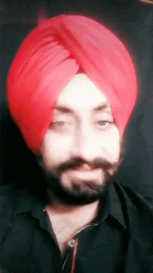a man wearing a red turban and black shirt looks at the camera