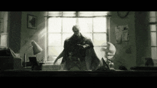 a black and white photo of a man in a cape standing in front of a window
