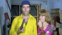 a man in a yellow shirt holding a gun next to a woman