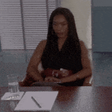a woman sits at a desk with a notebook and pen