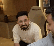 a man with a beard and glasses is sitting next to another man .