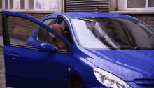 a woman is getting out of a blue car with her door open