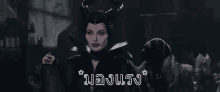 a woman in a black costume with horns is holding a black bird in her hand .
