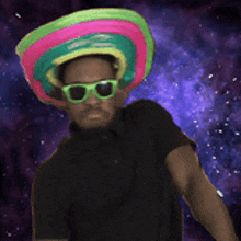 a man wearing a colorful sombrero and sunglasses stands in front of a galaxy