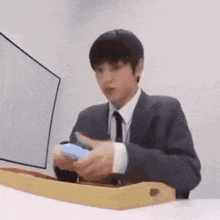 a man in a suit and tie is sitting at a table holding a video game controller .