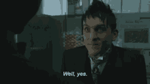 a man in a suit and tie is smiling and talking to another man in a kitchen .