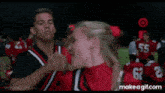 a group of cheerleaders are dancing on a field in red uniforms .
