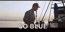 a man is standing on a boat with the words `` go blue '' written on the screen .