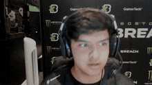 a man wearing headphones stands in front of a monster energy banner