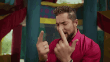 a man in a pink shirt is clapping his hands together