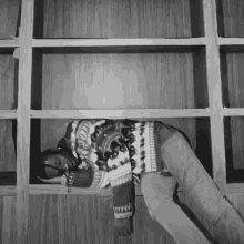 a black and white photo of a man sleeping in a shelf