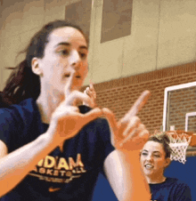 a woman is making a heart shape with her hands while playing basketball .