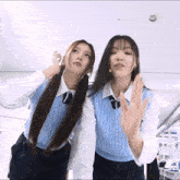 two girls are standing next to each other and one is wearing a sweater vest