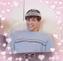 a man wearing a tiara is smiling while sitting at a laptop