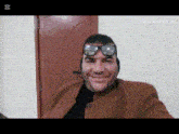 a man wearing sunglasses and ear muffs is smiling in front of a door
