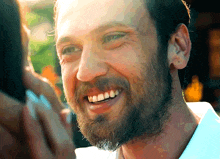 a man with a beard and a white shirt smiles