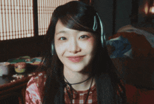 a woman wearing headphones and a choker smiles for the camera