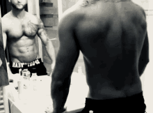 a shirtless man is looking at himself in the mirror