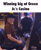 a man sitting in a chair playing a slot machine with the caption winning big at green jr 's casino