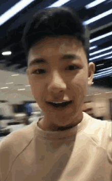 a young man wearing a white shirt is smiling and looking at the camera
