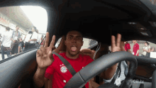 a man in a red shirt that says fc bayern is giving the peace sign